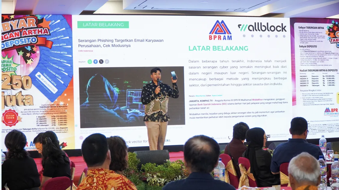 Pembicara Wallblock membawakan materi keamanan siber di depan tamu undangan Customer Gathering BPR Artha Mertoyudan, dengan slide berjudul Latar Belakang di layar.